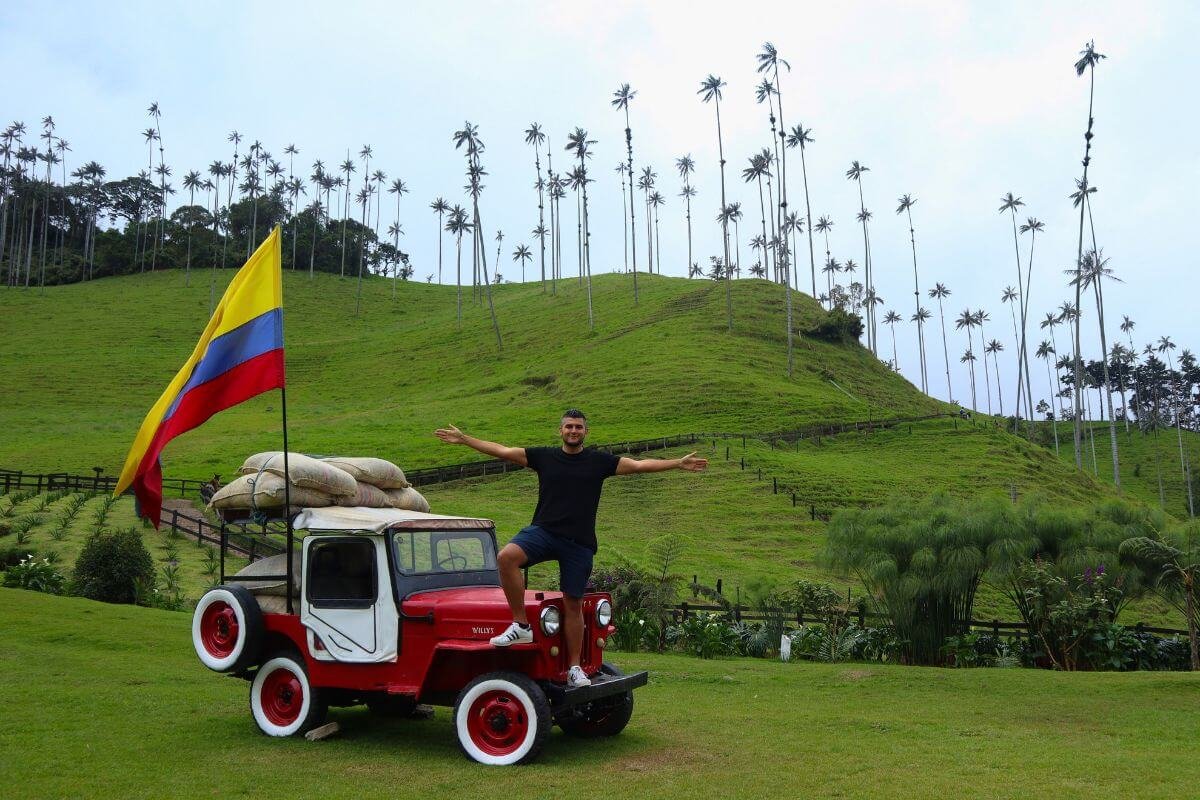 Man posing on a red Jeep with Colombian flag and wax palm trees in Cocora Valley
Title-Attribut: Jeep and wax palms in Cocora Valley