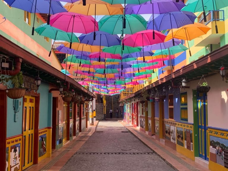 Colorful umbrella street in Guatape, Colombia, with traditional zócalos on both sides